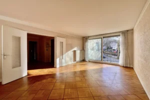 Séjour traversant d’un appartement 4 pièces à vendre à Paris 12 Bel Air, double exposition Est/Ouest, parquet d’origine, grande baie vitrée sur balcon et belle luminosité naturelle.