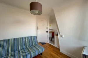 Pièce principale d’un appartement à Paris 15 avec parquet, belle hauteur sous plafond, entrée optimisée et circulation fluide vers l’espace cuisine.