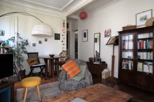 Salle à manger attenante au séjour d’un appartement à Paris 5, quartier des Gobelins, avec parquet ancien, moulures au plafond, mobilier chaleureux et circulation fluide entre les espaces.