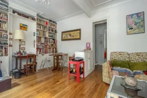 Salon avec espace salle à manger d’un appartement à Paris 17 Pont Cardinet, parquet ancien, grande bibliothèque intégrée, moulures au plafond et volumes chaleureux.