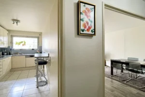 Cuisine indépendante d’un appartement à vendre à Paris 12 Picpus avec coin repas type bar, meubles blancs, plan de travail fonctionnel et fenêtre apportant une belle lumière naturelle.