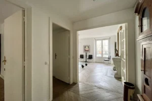 Entrée d’un appartement à vendre à Paris 11, boulevard du Temple, avec parquet en point de Hongrie, dégagement vers le séjour et portes anciennes.
