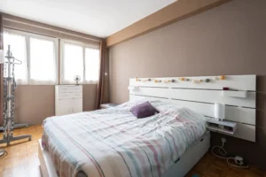 Chambre avec parquet, lit double, tête de lit avec rangements, fenêtre apportant une belle luminosité, appartement 2 pièces à Paris 12 secteur Dugommier Daumesnil.