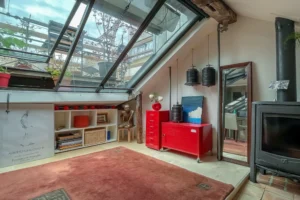 Verrière de toit type atelier apportant une lumière naturelle abondante dans un espace de vie sous les combles, appartement de caractère à Paris 10.