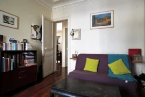 Chambre d’un appartement à Paris 5, quartier des Gobelins, avec parquet ancien, espace bureau et bibliothèque, circulation fluide vers le séjour et atmosphère calme.