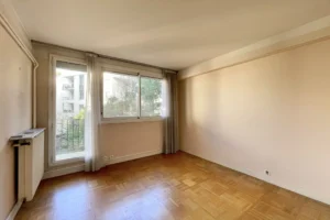 Chambre lumineuse d’un appartement 4 pièces à vendre à Paris 12 Bel Air, parquet d’origine, accès balcon, fenêtre sur extérieur arboré et calme résidentiel.
