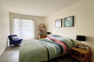 Chambre parentale d’un appartement à vendre à Paris 12 Picpus avec lit double, accès à une grande baie vitrée, fauteuil et atmosphère calme et lumineuse.