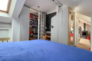 Chambre sous combles avec rangements intégrés et espace dressing dans un appartement de caractère à Paris 10.