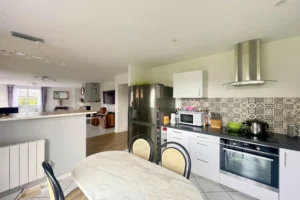 Cuisine équipée avec électroménager, crédence graphique et espace repas, maison à vendre à Saint-Benoît-d’Hébertot.