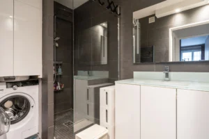 Salle d’eau moderne avec douche à l’italienne vitrée, meuble vasque avec miroir, carrelage gris, emplacement lave-linge, appartement 2 pièces à Paris 12 Dugommier Daumesnil.