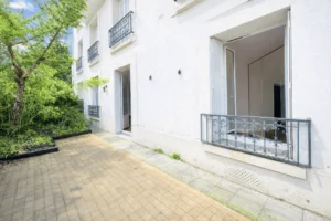 Terrasse privative d’un appartement en duplex à vendre Paris 12 Porte de Vincennes, située en rez-de-jardin, avec façade claire, garde-corps en fer forgé et environnement arboré Avenue Saint-Mandé.