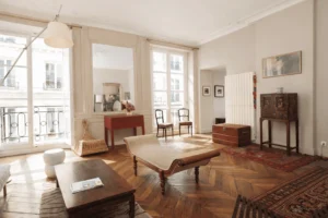 Séjour lumineux avec parquet en point de Hongrie, moulures anciennes, grande hauteur sous plafond et mobilier ancien, appartement familial Paris 2 Sentier place du Caire.