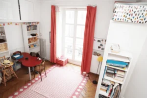 Seconde chambre lumineuse avec rangements et coin travail, parquet ancien et atmosphère calme.