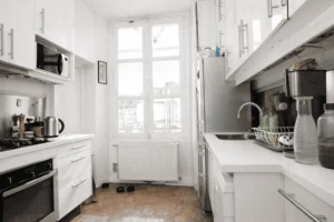 Cuisine indépendante équipée, linéaire blanc, plan de travail, évier inox et grande fenêtre, cuisine fonctionnelle Paris 2.