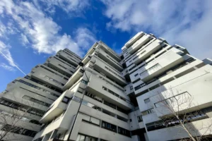 Perspective en contre-plongée d’un immeuble des années 1960 à Paris 12 Reuilly Diderot, façade blanche avec balcons filants et volumes architecturaux typiques de l’époque.