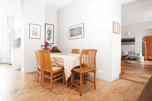 Salle à manger attenante à la cuisine, sol en tomettes anciennes, table familiale et lumière naturelle, appartement Paris 2 Sentier.