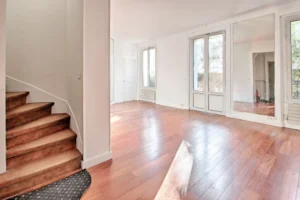 Grande pièce de vie en duplex à vendre Paris 12 Porte de Vincennes, parquet massif, mur miroir agrandissant l’espace et belle luminosité traversante exposée sud Avenue Saint-Mandé.