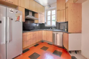 Séjour d’un appartement en duplex à vendre Paris 12 Porte de Vincennes avec escalier intérieur menant à l’étage, parquet massif et grandes ouvertures sur terrasse.
