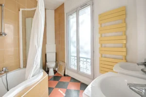 Cuisine indépendante équipée avec meubles en bois, plan de travail sombre et fenêtre sur cour, appartement en duplex à vendre Paris 12 Porte de Vincennes Avenue Saint-Mandé.