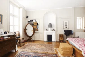 Chambre parentale spacieuse avec cheminée décorative, parquet ancien et rangements intégrés, belle hauteur sous plafond.