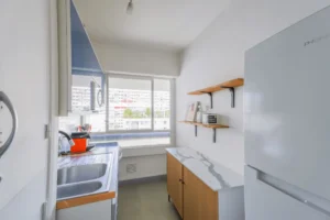 Cuisine indépendante équipée d’un appartement 2 pièces à Paris 12 Reuilly Diderot avec plan de travail, étagères murales et fenêtre offrant une vue dégagée.