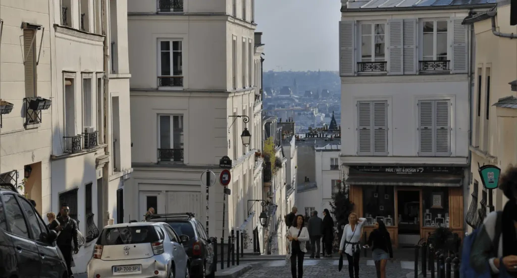 Rue en pente à Montmartre avec immeubles anciens et vue dégagée sur Paris dans le 18e arrondissement