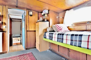 Cabine de péniche avec lit intégré, boiseries d’origine et rangements dans un espace cosy à Levallois-Perret quai Charles Pasqua.